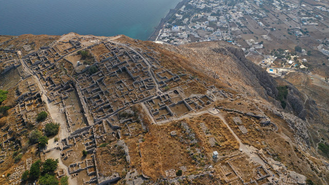 Aerial drone photo of iconic archaeological site of ancient Thera or Thira built uphill with amazing views to Kamari and Perissa beaches and seaside villages, Santorini island, Cyclades, Greece