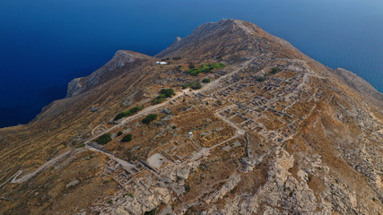 Fototapeta premium Aerial drone photo of iconic archaeological site of ancient Thera or Thira built uphill with amazing views to Kamari and Perissa beaches and seaside villages, Santorini island, Cyclades, Greece