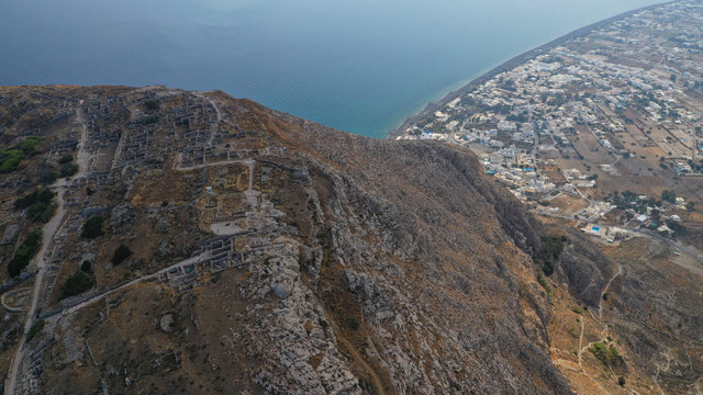 Aerial drone photo of iconic archaeological site of ancient Thera or Thira built uphill with amazing views to Kamari and Perissa beaches and seaside villages, Santorini island, Cyclades, Greece