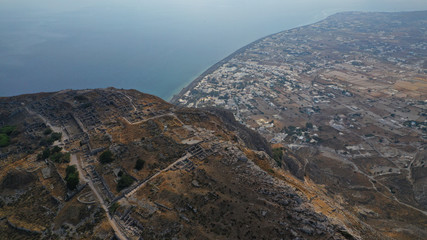 Aerial drone photo of iconic archaeological site of ancient Thera or Thira built uphill with amazing views to Kamari and Perissa beaches and seaside villages, Santorini island, Cyclades, Greece