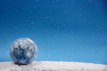 Fototapeta na wymiar Christmas ball on snowy background stock images. Christmas ball isolated on snow background. Blue Christmas ball. Christmas decoration on a blue background with copy space for text