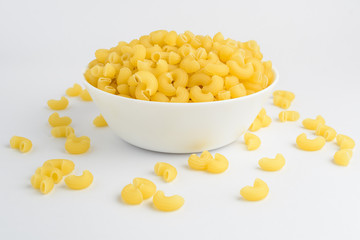 Group of dried corneti rigati Italian pasta in a white bowl ready to be cooked, isolated on white table, side view