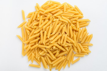 Group of dried penne Italian pasta in a round shape ready to be cooked, isolated on white table, with view from above 