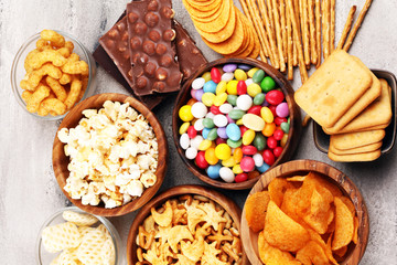 Salty snacks. Pretzels, chips, crackers in wooden bowls and candy and chocolate on table