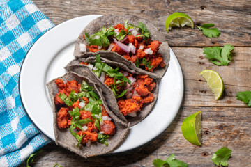 Mexican chorizo tacos with blue corn tortillas on wooden background