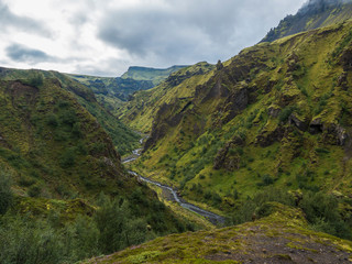 Fototapeta na wymiar Landscape of Godland and thorsmork with rugged green moss covered rocks and hills, bending river canyon, Iceland, Fimmvorduhals hiking trail. Summer cloudy day.