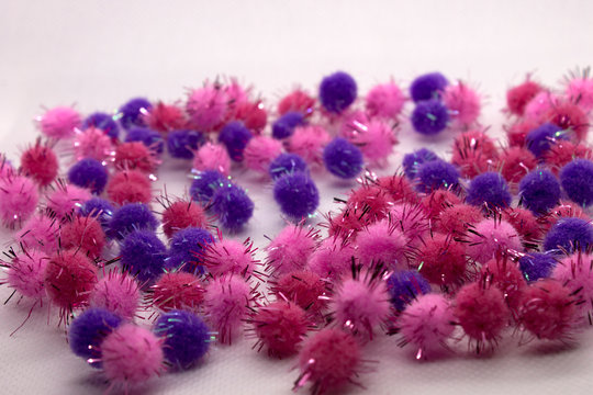 This is a photograph of Pink and Purple Pom Poms isolated on a White background