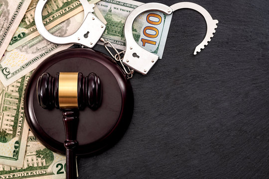 Bail bond system, bailing out of jail and innocent until proven guilty conceptual idea with judge wooden gavel, dollar banknotes and handcuffs with copy space