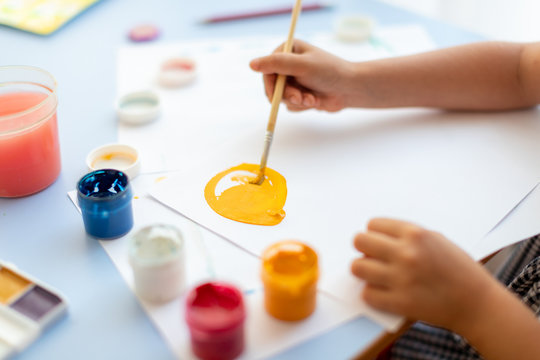 Just a few moments and picture will be done. Little girl is drawing by using gouache and brush. Learning in the art class.