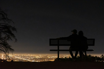 Couple on a bench at night looking over the city
