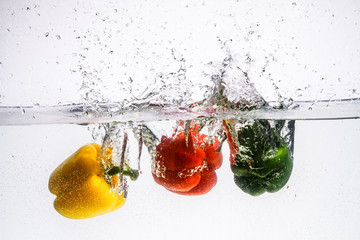 Fototapeta na wymiar three peppers falling in water