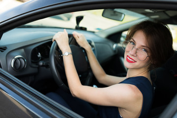 Fototapeta na wymiar Portrait of a successful business woman in a car salon, beautiful brunette with a smile on her face