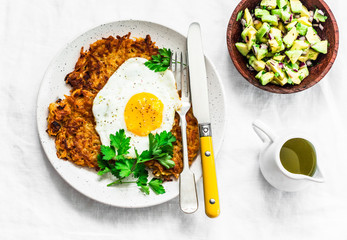 Sweet potato rostis with fried egg and avocado salsa on light background, top view