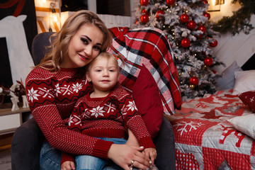 Smiling joyful mom with her daughter near the Christmas tree