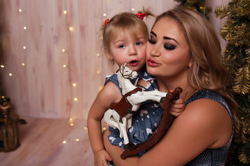 Smiling joyful mom with her daughter near the Christmas tree