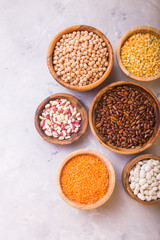 Legumes, lentils, chikpea and beans assortment in different bowls on white table top view.
