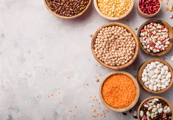 red Lentils, chikpea and beans assortment in different bowls on white stone  table top view.