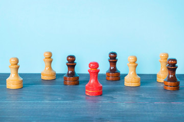 Standing out of the crowd and leadership concept, red pawn between typical chess figures.
