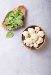Fresh organic cauliflower cut into small pieces in wooden  bowl on stone background