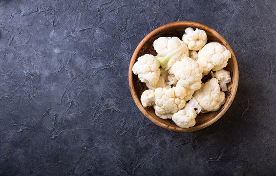 Fresh organic cauliflower cut into small pieces in wooden  bowl on stone background