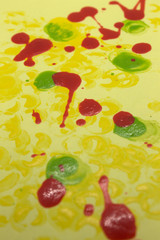 This is a photograph of Red,Green and Yellow nail polish splattered onto a Yellow paper