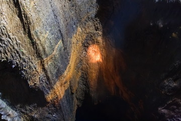 The ceiling and walls of the lava cave are covered with a red organic coating. The view opening in front of cavers