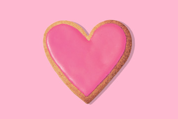 Decorated heart shaped cookie on pink background, top view