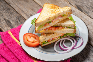 Grilled cheese sandwich with tomato and whole grain bread on wooden background