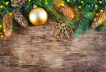 Christmas background with spruce branches, golden ornaments and pine cones on wooden background,