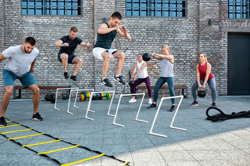 Group of people working out and jumping over hurdles