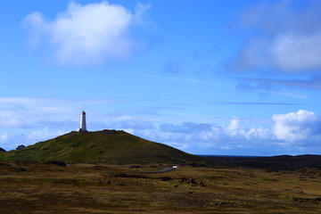 paisaje en islandia con un faro en una monta&ntilde;a y el cielo azul