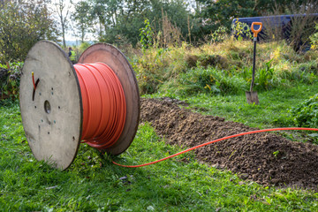 Wooden spool with fiber optic cable for fast internet ready to be laid in narrow trenches in the...
