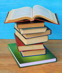 An open book lying on a stack of books in on a wooden table. Vertical 