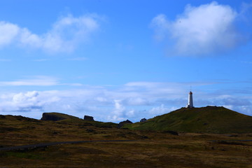 Fototapeta na wymiar paisaje en islandia con un faro en una montaña y el cielo azul