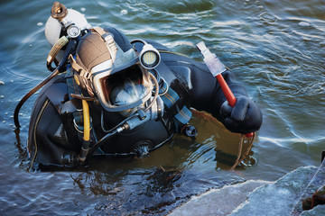 industrial diver with scuba gear and hammer working in the water at the shore reinforcement, copy...