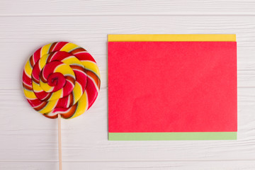 Multicolored round lollipop and paper card. Sweet candy on stick and blank paper sheet. Greeting...