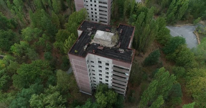 Flying a drone over Pripyat around a tall house, rotating clockwise old part city