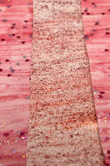 This is a photograph of an abstract background created by organizing stripes created using pink glitter paint and heart sequins