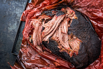 Traditional barbecue wagyu pulled beef in peach paper as top view on a rustic board