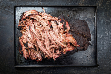 Traditional barbecue wagyu pulled beef offered as top view on a rustic board in a metal tray