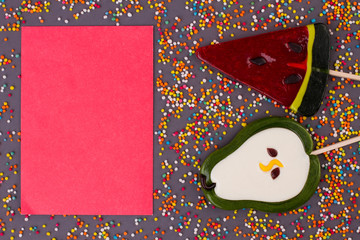 Composition with tasty lollipops on black background. Lollipops in different shapes and blank paper...