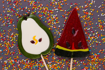 Lollipops in a shape of pear and watermelon. Big tasty lollipops and colored sprinkle candies on...