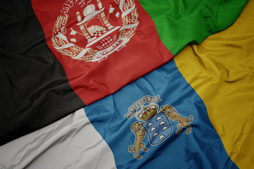 waving colorful flag of canary islands and national flag of afghanistan.
