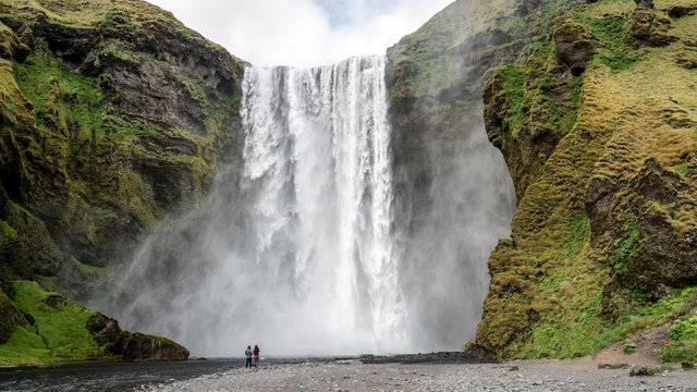 Huge waterfall of Skogafoss with a couple taking photographs, Skogar, south of Iceland