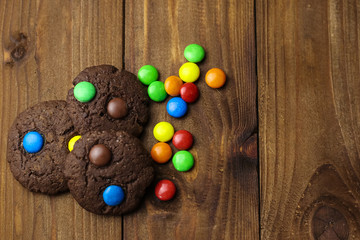 Tasty brownie cookies with colorful candies on table, close up