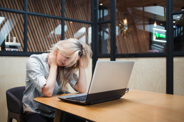 Stressful young business woman sitting at the table and working on a problematic issue