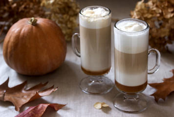 Homemade pumpkin latte in tall glasses and pumpkin on a linen tablecloth. Rustic style.