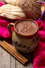 Mexican hot chocolate with sweet conchas bread on wooden background