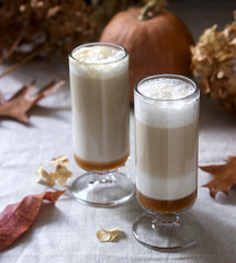 Homemade pumpkin latte in tall glasses and pumpkin on a linen tablecloth. Rustic style.