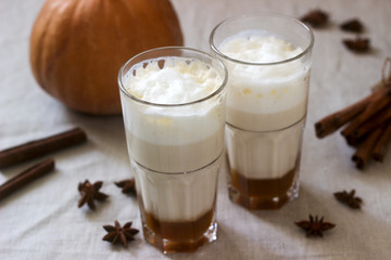 Homemade pumpkin latte in tall glasses and pumpkin on a linen tablecloth. Rustic style.